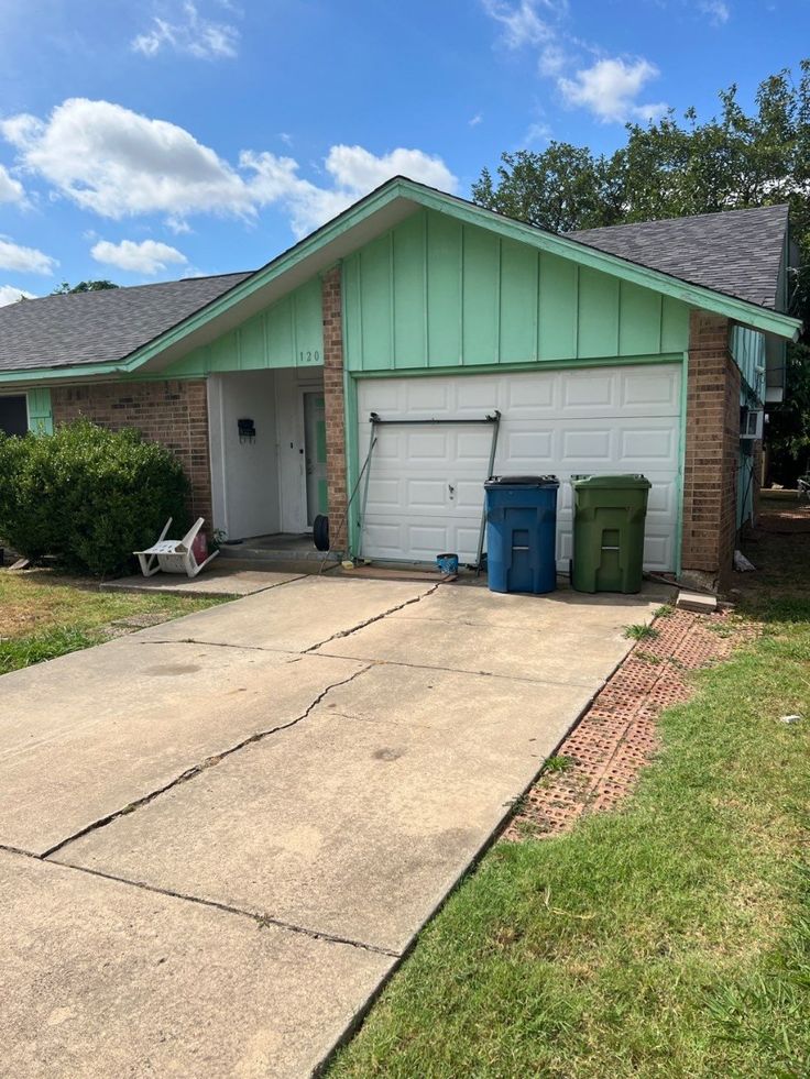 Fixer-upper house with a cracked driveway and a damaged garage door